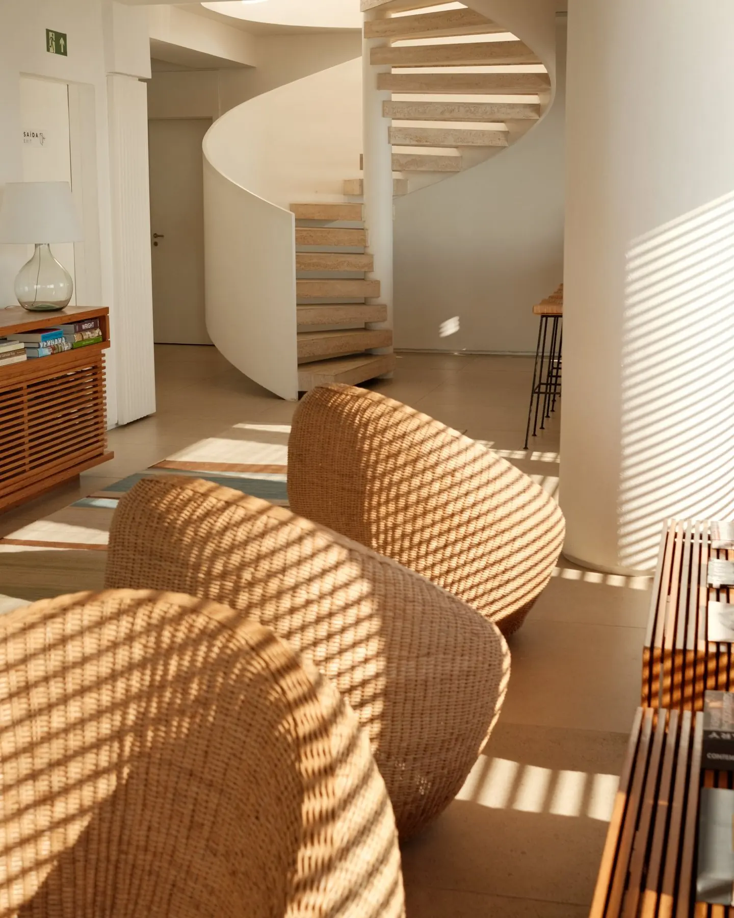 Striped afternoon light across wicker chairs and a white spiral staircase