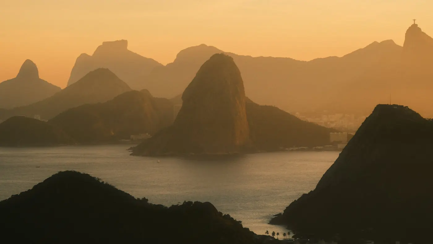 Sugarloaf Mountain and Christ the Redeemer in golden haze across Guanabara Bay